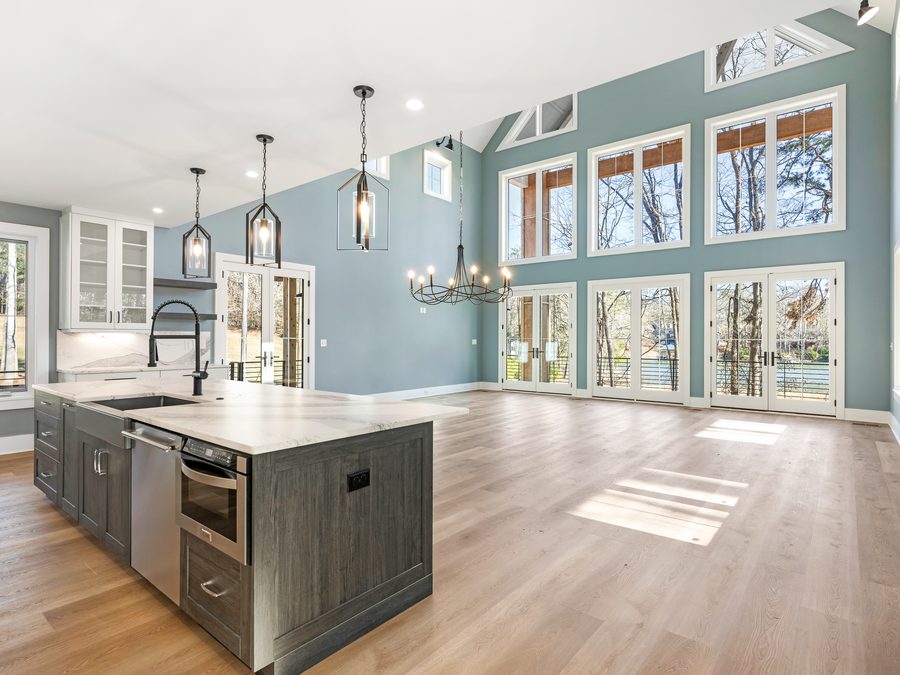 Kitchen with a dark island, pendant lighting, and a wall of windows over the range