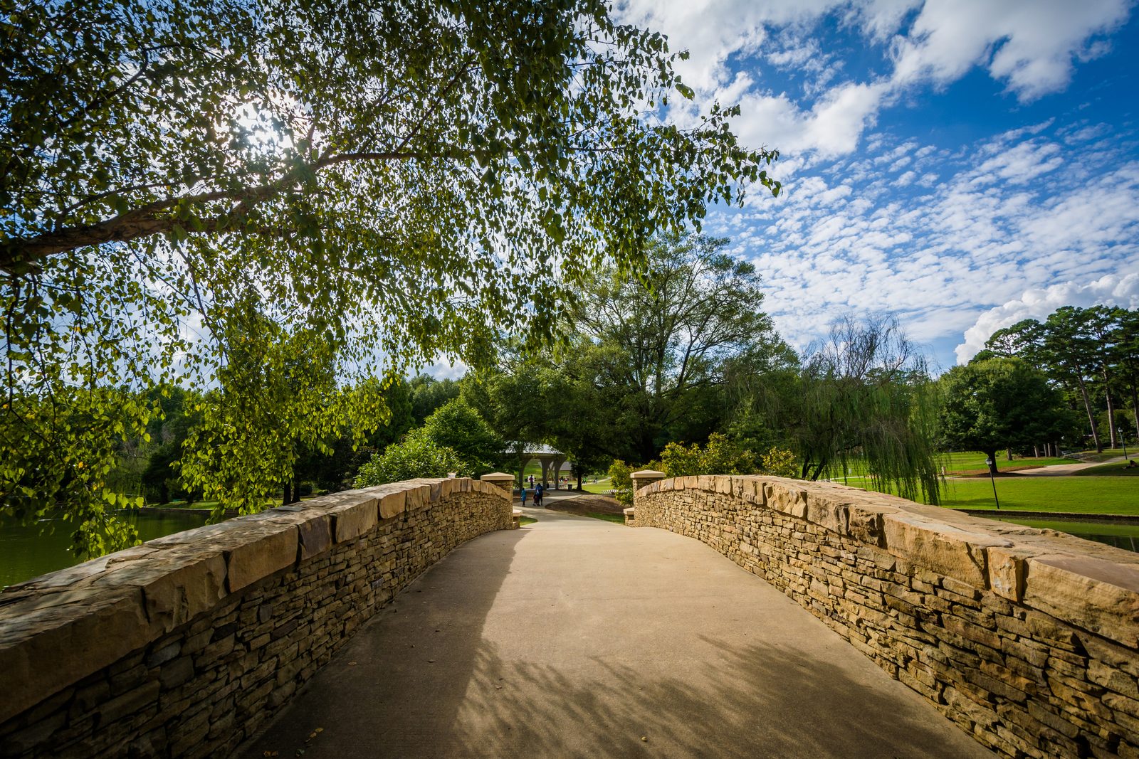 A stone garden wall running alongside a shaded walking path