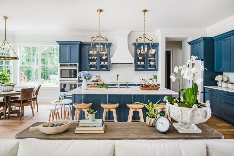 Kitchen with navy cabinetry, brass hardware, and a large island under pendant lighting