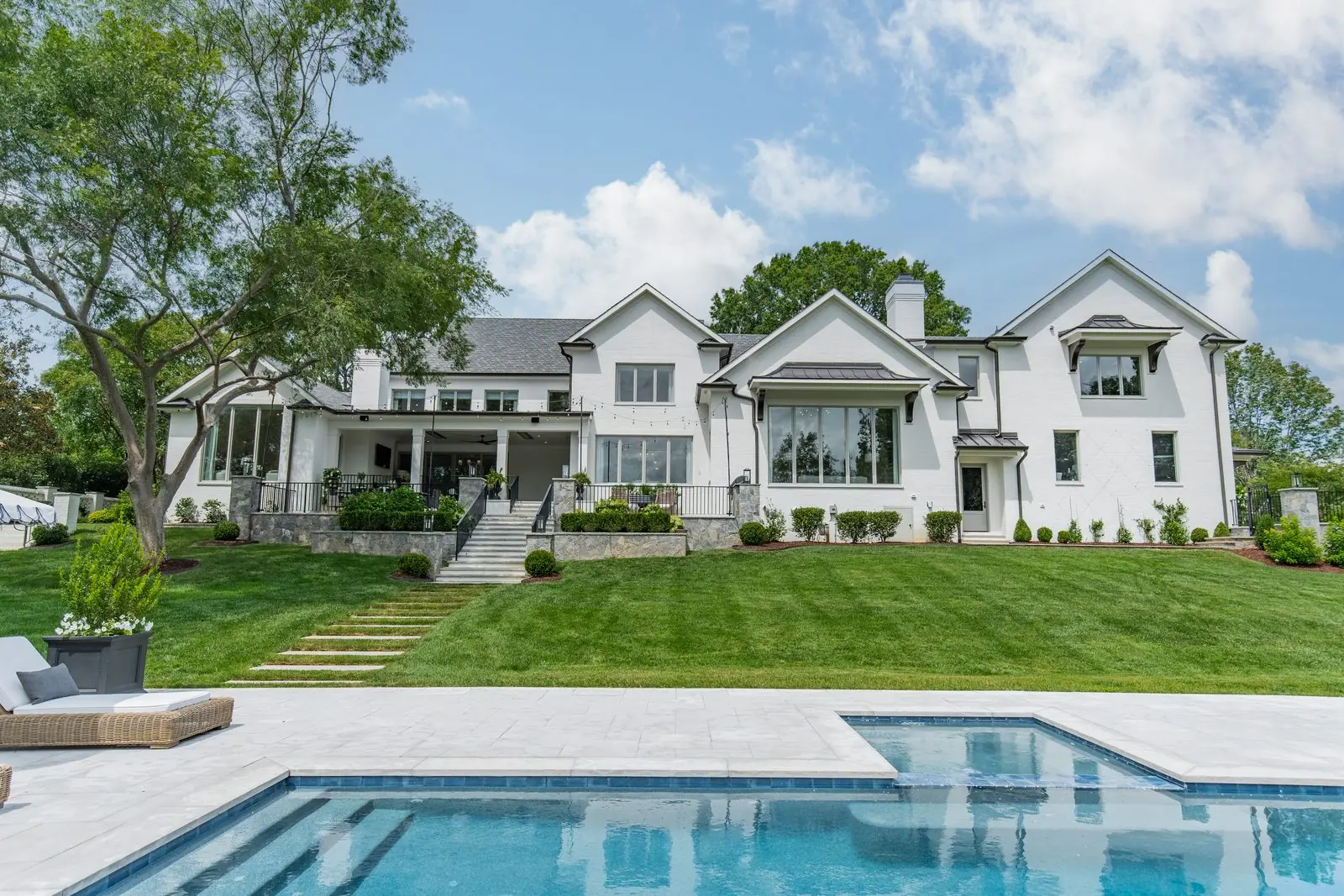 An Everett Custom Homes residence seen across the lawn, with a pool terrace in the foreground