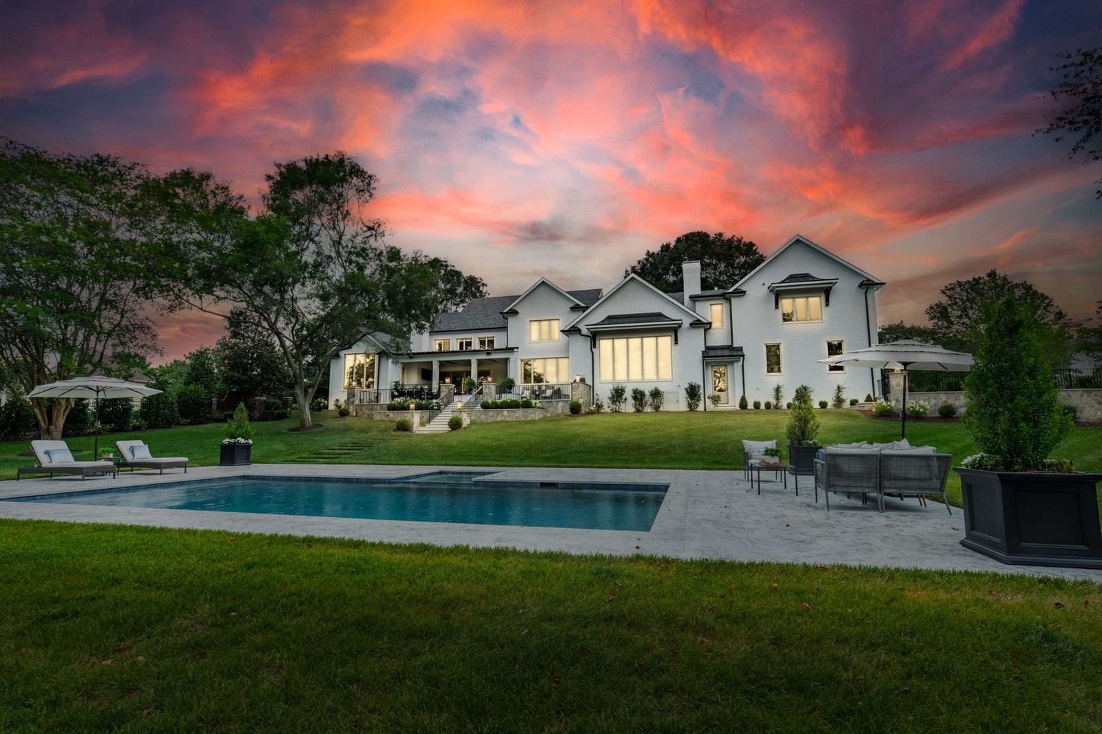 An Everett Custom Homes residence at twilight, with a pool and terrace along the rear elevation