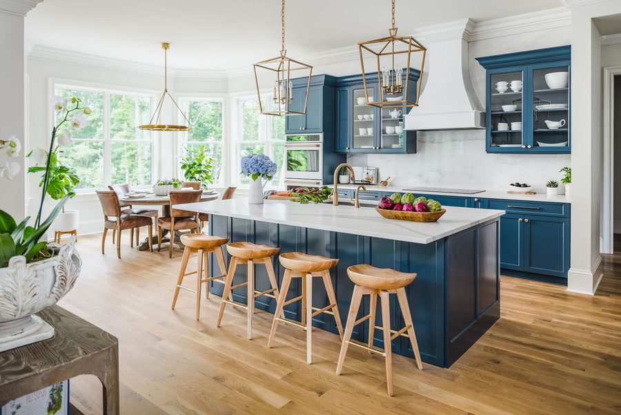 Custom kitchen with a navy island, brass pendant lights, and glass-front upper cabinetry