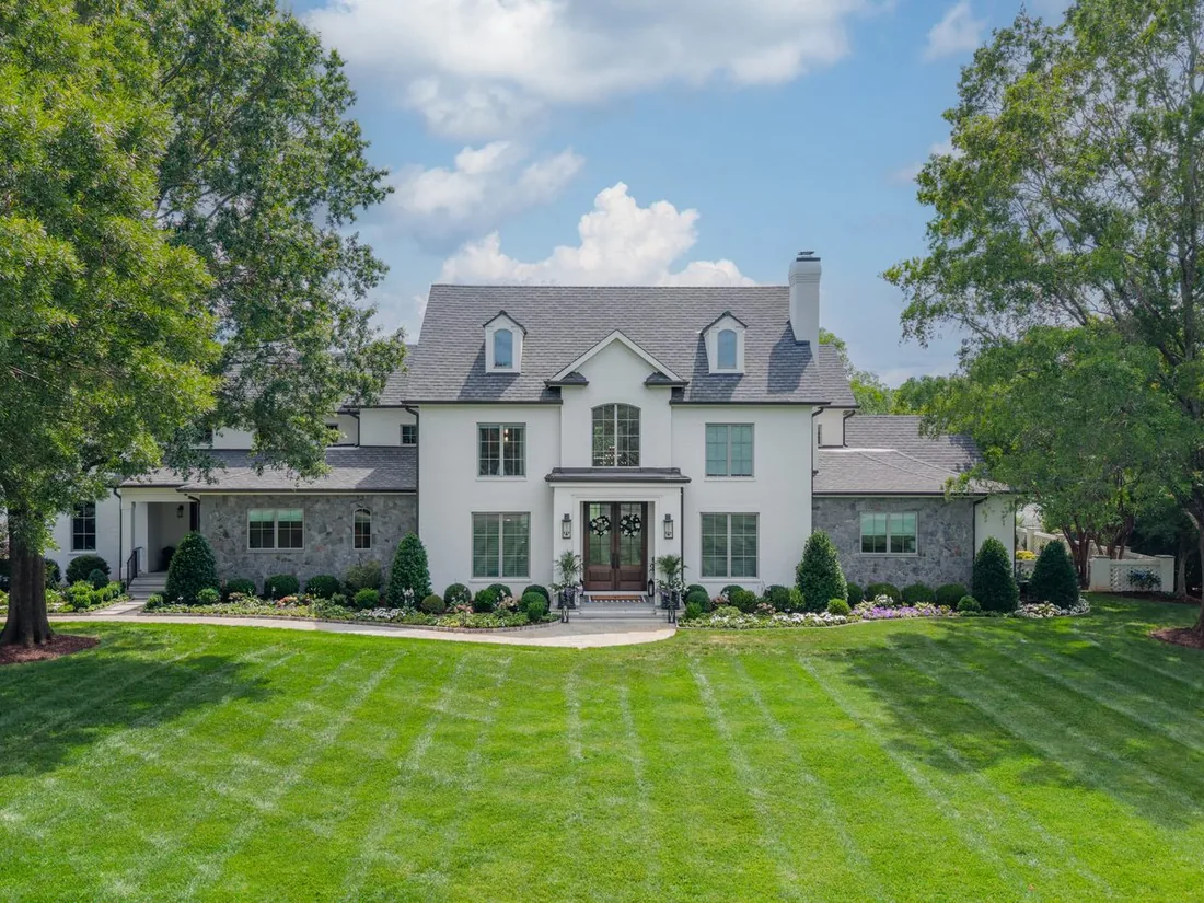 Waldon after its whole-home renovation, with a white lime-slurry exterior, stone wings and a broad front lawn