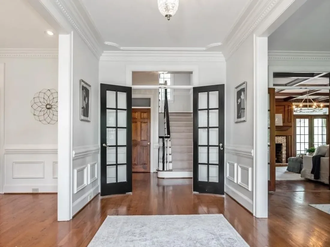 The original Waldon foyer, a narrow entry with black French doors and a closed stair beyond