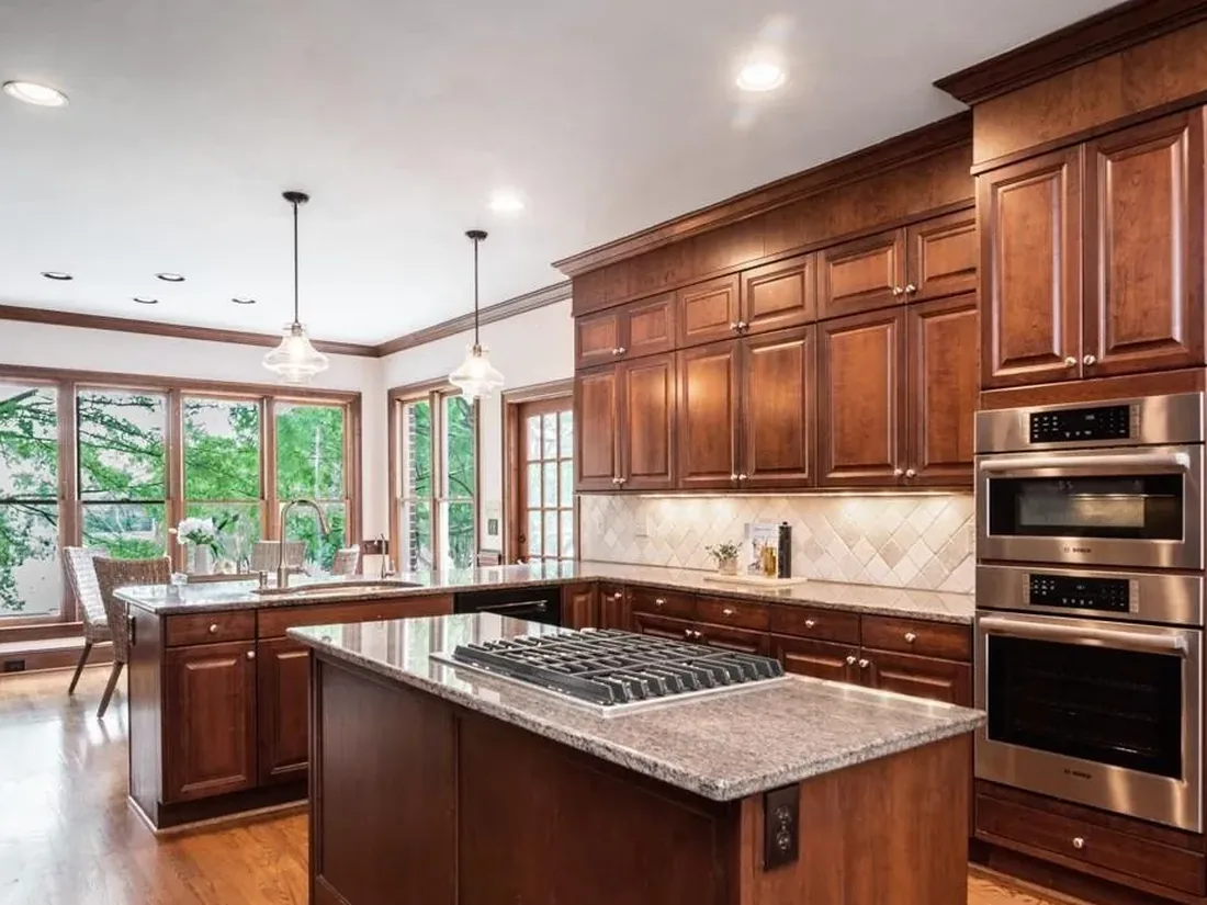 The original Waldon kitchen with dark cherry cabinets, granite counters and a cooktop island