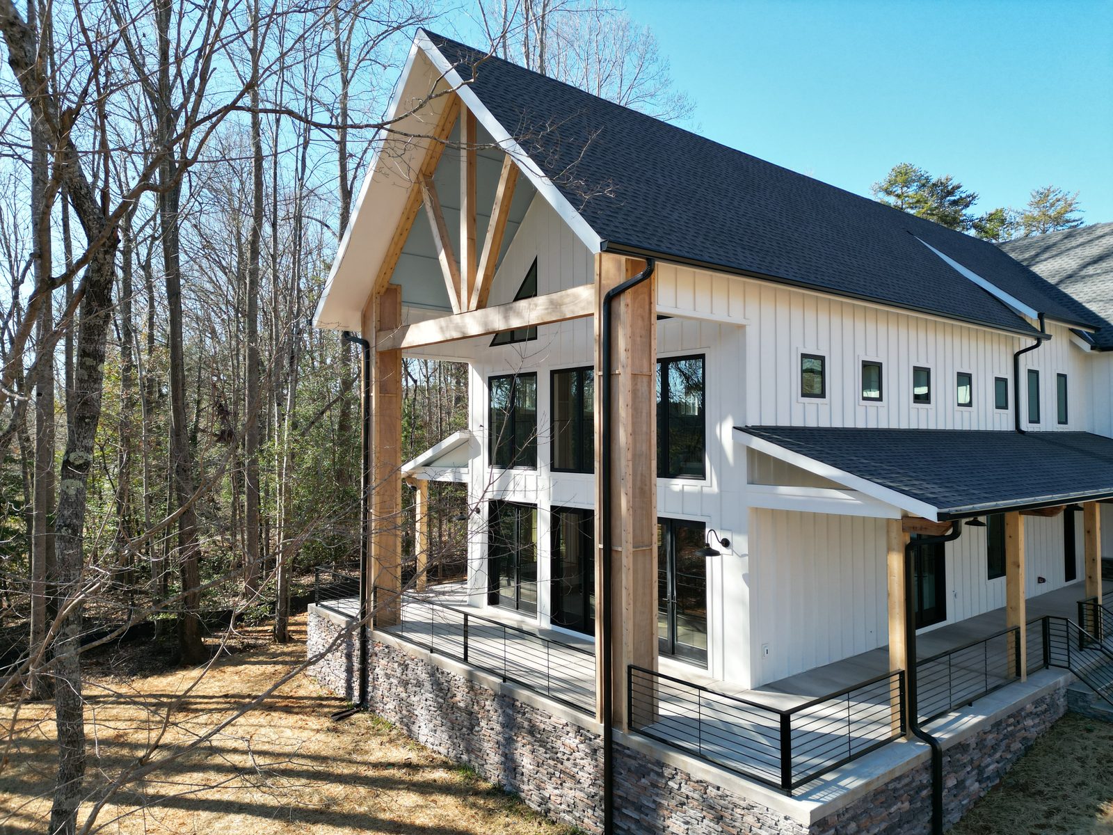 A timber-framed Everett Custom Homes exterior with exposed beams, black metal roof, and board-and-batten gables.