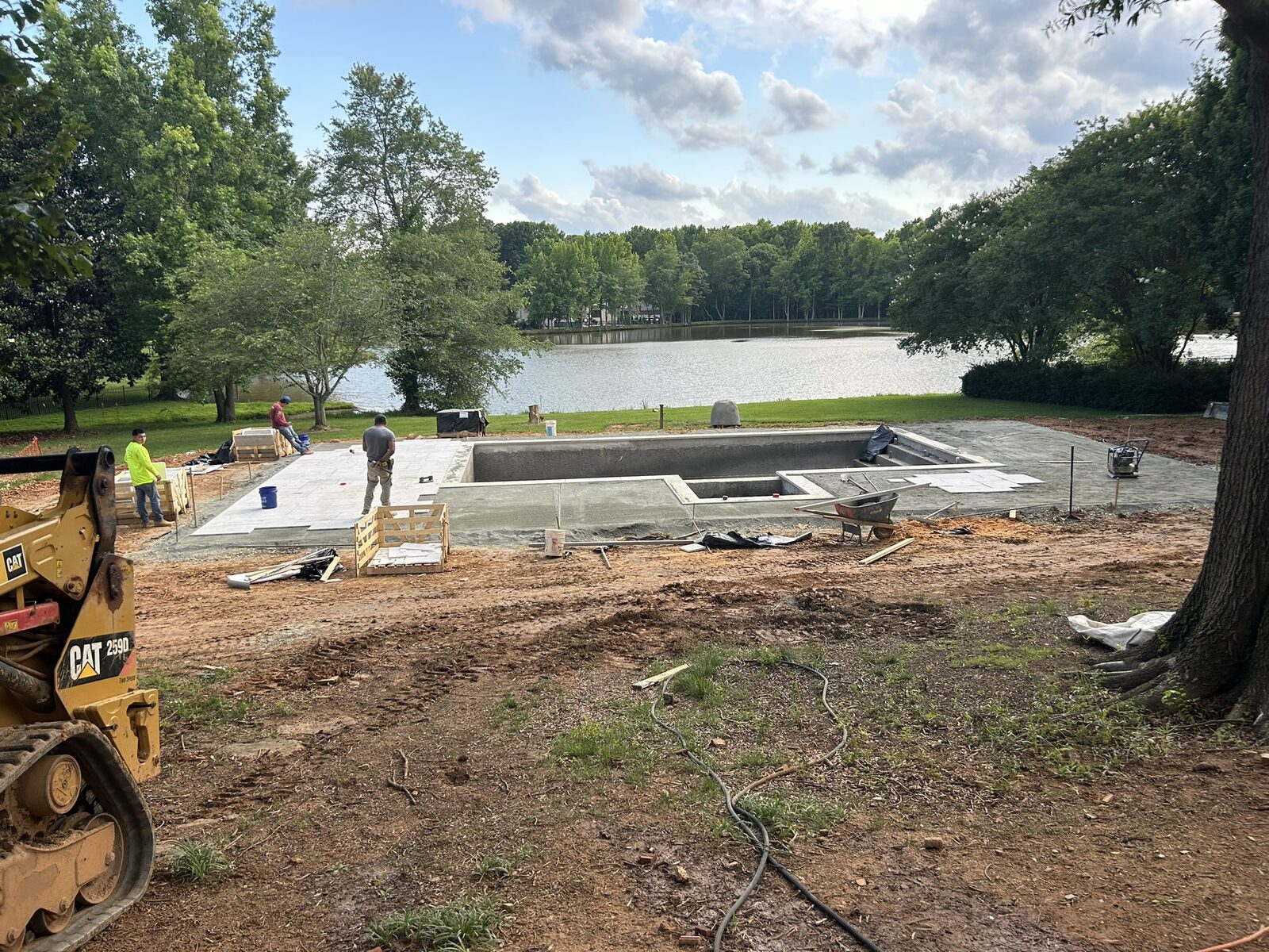 The new pool shell and surrounding concrete decking being installed on the lakefront, squared to the sight lines of the rebuilt home.
